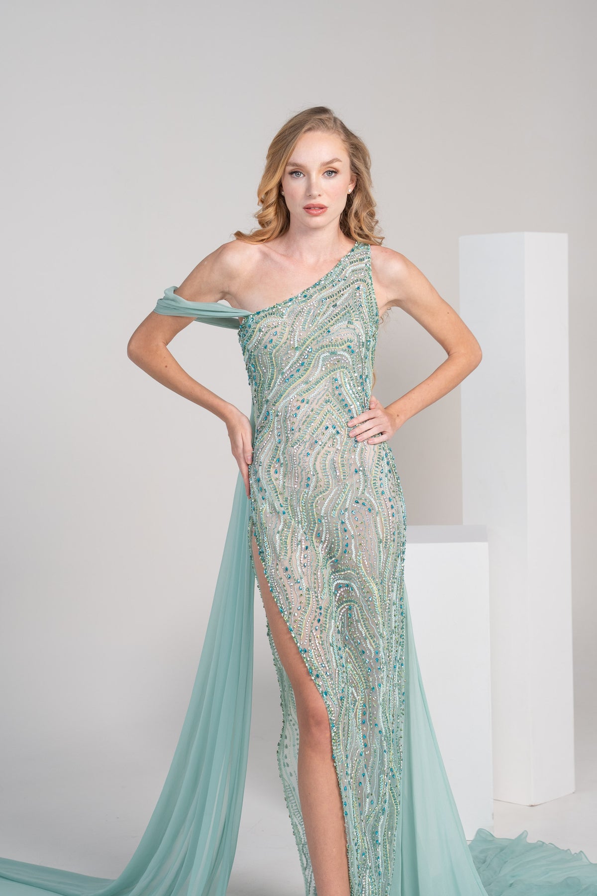 A green dress with intricate embroidery, a side slit and a flowing chiffon shwal.