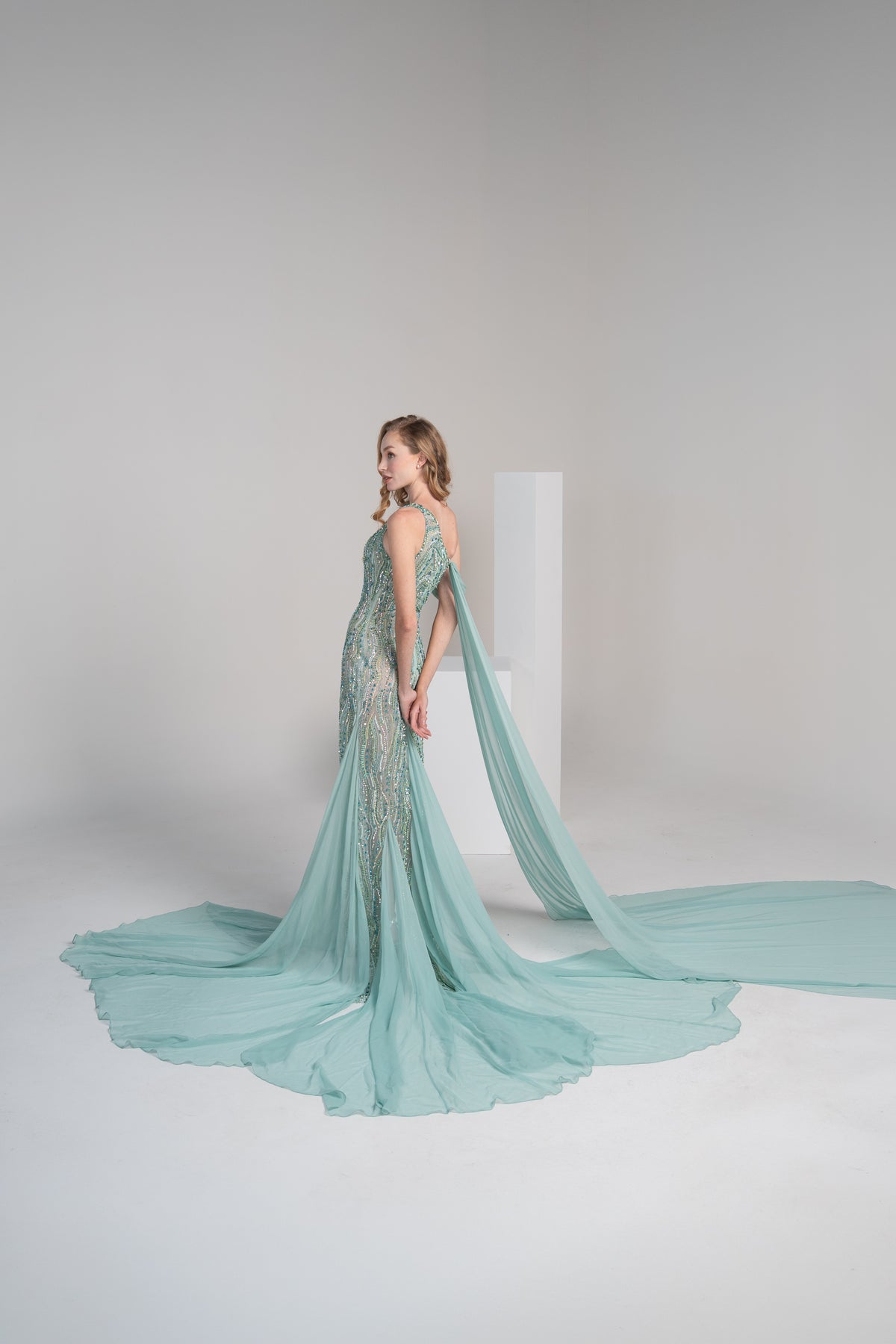 A green dress with intricate embroidery, a side slit and a flowing chiffon shwal.